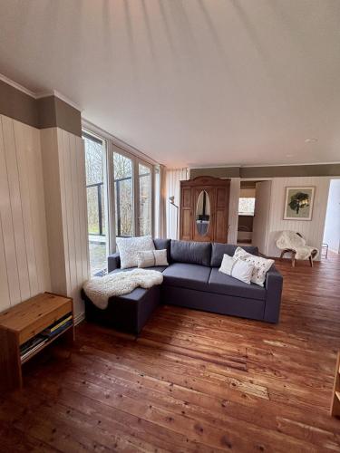 a living room with a blue couch and wooden floors at Beach Hangout Hygge in Den Burg