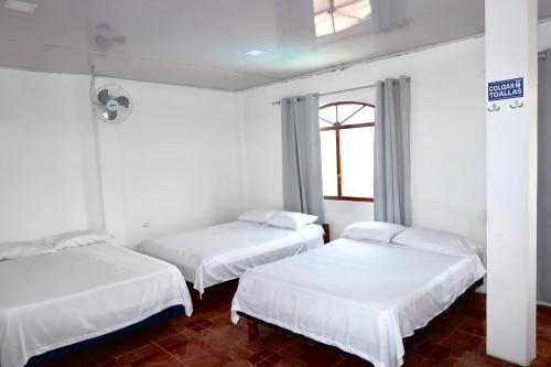 zwei Betten in einem weißen Zimmer mit Fenster in der Unterkunft ECUADOR Hotel Pedernales MrRobert in Pedernales