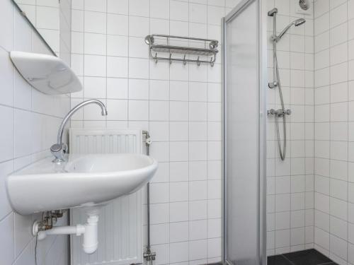 La salle de bains blanche est pourvue d'un lavabo et d'une douche. dans l'établissement Comfortable cottage with WiFi at 50 m from the Oosterschelde, à Wemeldinge