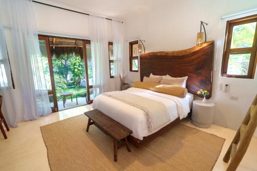 a bedroom with a large bed with a wooden headboard at Mikasa Bacalar Hotel Boutique, Lagoon Front in Bacalar