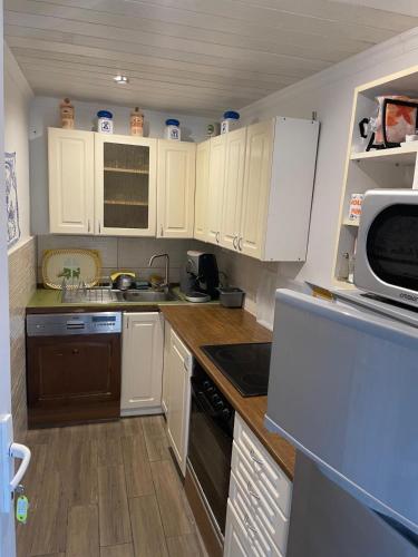 a small kitchen with white cabinets and a microwave at Dombi Porta in Erdőbénye