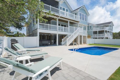 a house with a swimming pool and patio furniture at 4918 - Stress Less in Kitty Hawk
