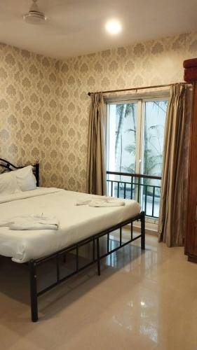 a bedroom with a bed and a large window at Pool View Apartment - Sunshine By Leela Homes in Arpora