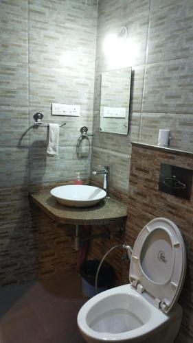a bathroom with a white toilet and a sink at Pool View Apartment - Sunshine By Leela Homes in Arpora