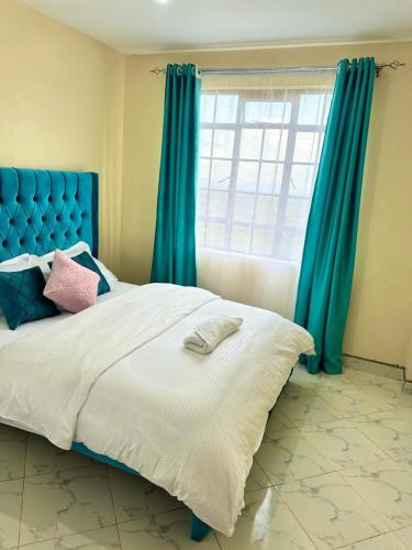 a bedroom with a bed with a blue headboard and a window at Executive two bedroom embu by Tsparks in Meru