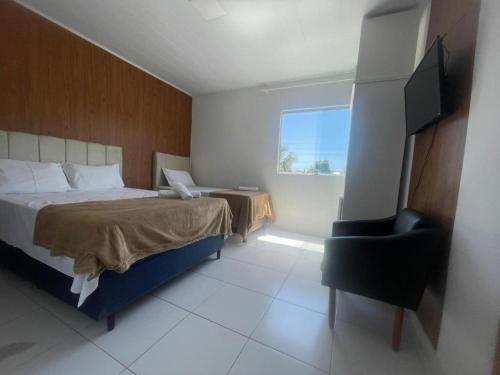a bedroom with a bed and a chair and a television at Pousada Terraço das Aguas in Maceió