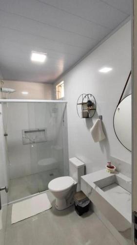 a white bathroom with a shower and a toilet at Pousada Terraço das Aguas in Maceió
