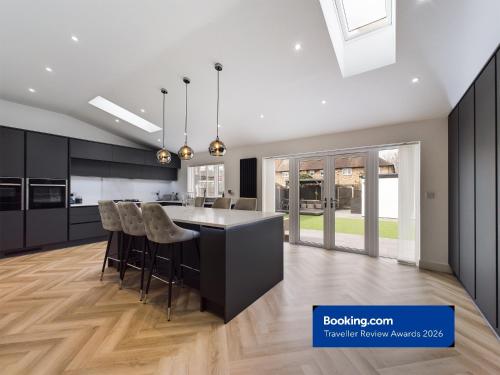 a kitchen with black cabinets and a island with bar chairs at Luxury Modern Spacious House in Hull