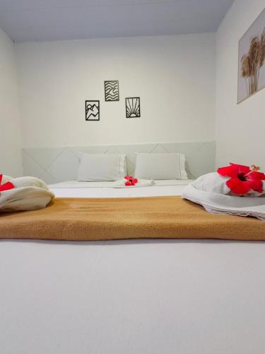 a white bed with red flowers on top of it at Pousada do Trinta in Fernando de Noronha