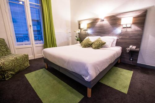 a hotel room with a large bed and a chair at Hotel Actuel Chambéry Centre Gare in Chambéry