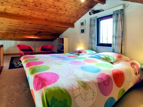 ein Schlafzimmer mit einem großen farbenfrohen Bett mit roten Stühlen in der Unterkunft Cozy bungalow with large enclosed garden in Baillamont
