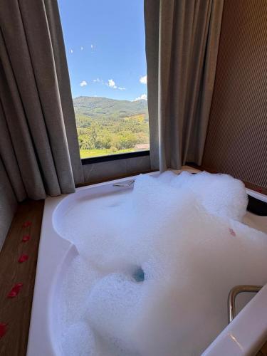 a bath tub filled with foam next to a window at Pousada Varandas de Minas in Monte Verde