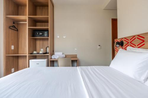 a bedroom with a large white bed and wooden cabinets at Vektor Itabirito in Itabirito