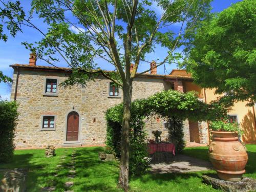 een oud stenen huis met een boom ervoor bij Belvilla by OYO Lovely agritourismo near Cortona in Cortona
