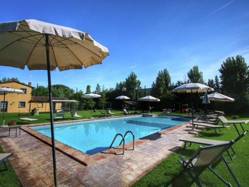 a swimming pool with chairs and umbrellas and a pool at Belvilla by OYO Lovely agritourismo near Cortona in Cortona