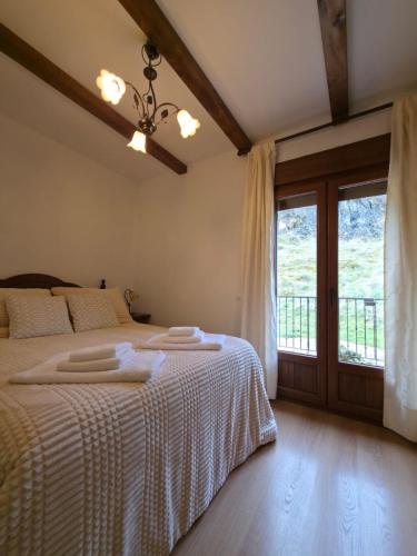 a bedroom with a bed with white sheets and a window at Casa Rural Raíces del Alto Tajo in Armallones