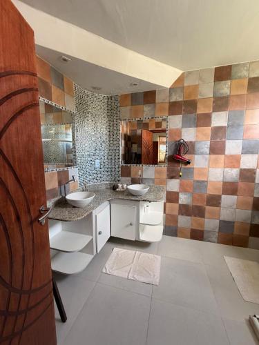 a bathroom with two sinks and a tiled wall at Villa Amarela in Itacimirim