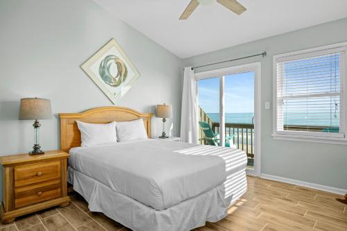 a bedroom with a bed and a balcony with the ocean at Didjeridu West by Emerald Isle Realty in Emerald Isle