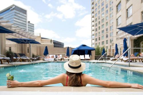 a woman in a hat sitting in a swimming pool at The Ritz-Carlton, Dallas in Dallas