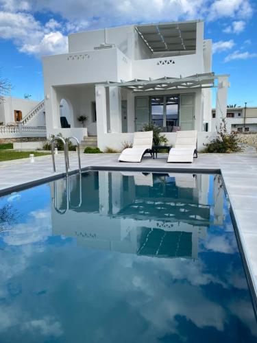 a villa with a swimming pool in front of a house at Zandre Luxury Suites in Skiros