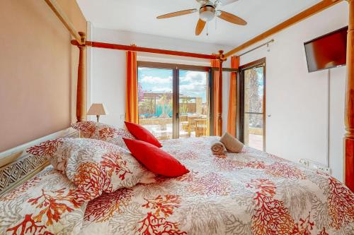 a bedroom with a bed with red pillows and a ceiling fan at Villa Cora - Traumvilla mit privatem Tennisplatz & beheiztem Pool in Triquivijate