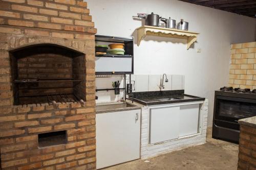 a kitchen with a brick wall and a brick oven at Casa com Varanda, Quintal e Churrasqueira em Bonito PE in Bonito