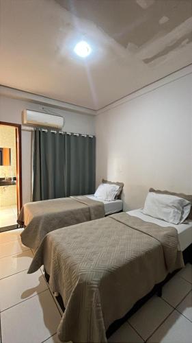 two beds in a hotel room with a window at Hotel Luz in Fronteira