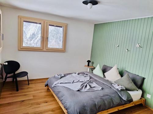 a bedroom with a bed and a chair and a window at Casa Castanea in Breiten