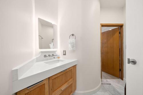 a white bathroom with a sink and a mirror at Brighton Carriage House in Rosemary Beach