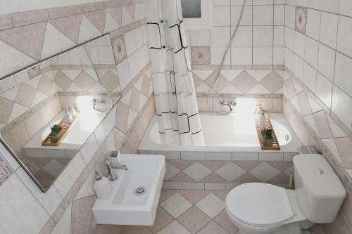 a bathroom with a toilet and a sink and a tub at LD Home in Lixouri