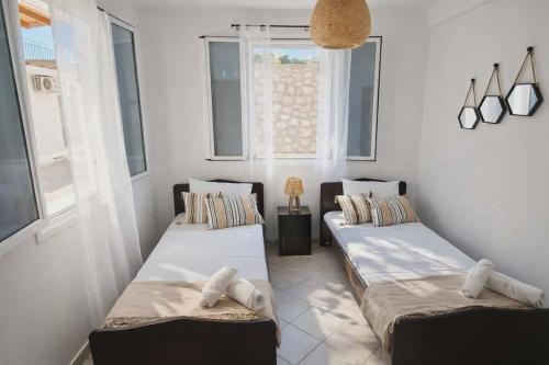 two beds in a room with two windows at LD Home in Lixouri