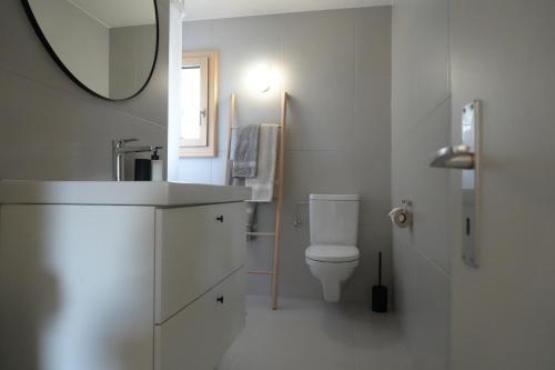 a white bathroom with a toilet and a mirror at Casa Castanea in Breiten