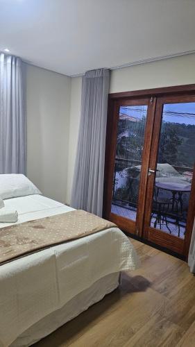 a bedroom with a bed and a large glass door at Casa Violeta in Ouro Preto