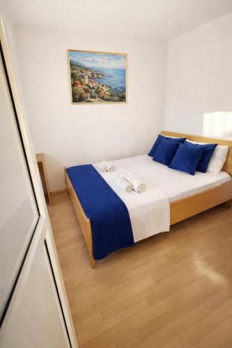 a bedroom with a large bed with blue pillows at Apartman David in Postira