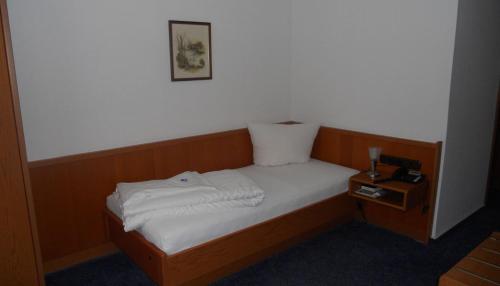 a small bed in a room with a night stand at Hotel am Hexenturm in Jülich
