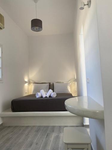 a bedroom with a bed with two pillows and a table at LEIVADAROS apartments in Perissa