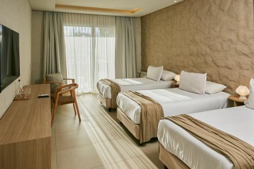a hotel room with two beds and a television at Howard Johnson Alcántara Boutique Hotel Chacras de Coria, Mendoza in Chacras de Coria