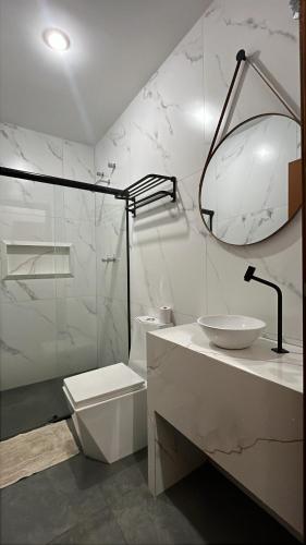 a white bathroom with a sink and a toilet at Hotel Luz in Fronteira