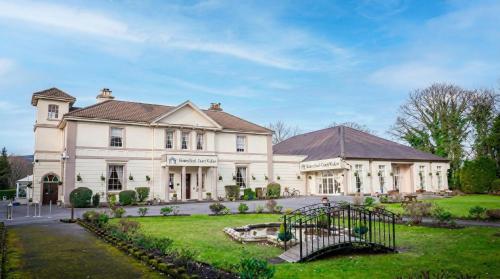 a large white house with a playground in the yard at Manor Park Country House in Swansea