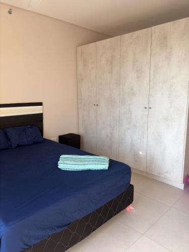a bedroom with a bed with blue sheets and cabinets at Modern Studio with Balcony in Asunción