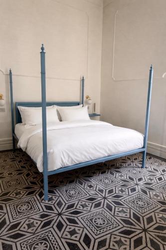 a bed with a blue frame in a room with a floor at Dimora di Duen - Villa Storica di Charme in Villa San Giovanni