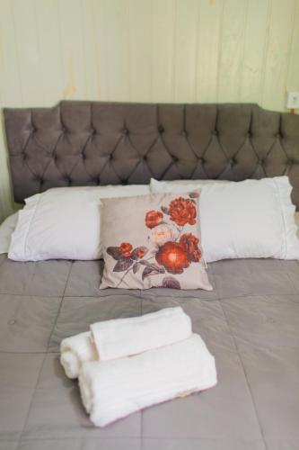 a bed with three pillows and towels on it at Chalé 10 min do centro in Gramado