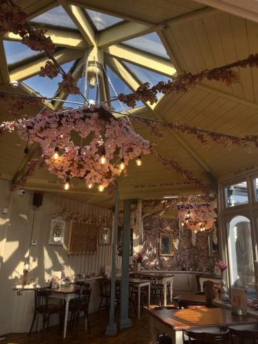 a dining room with tables and flowers hanging from the ceiling at The Cartologist in Durham