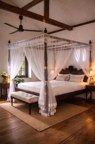 a bedroom with a canopy bed with a bench at Agwe Villa - Hikkaduwa in Dodanduwa