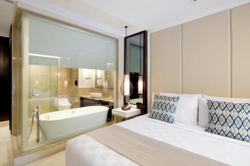 a bedroom with a large bed and a bath tub at Jambuluwuk Oceano Seminyak Hotel in Seminyak