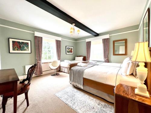 a bedroom with a large bed and a desk and a room at Colthrop Manor B&B in Thatcham