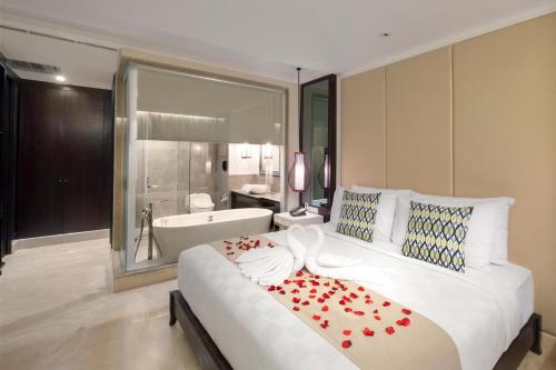 a bedroom with a large bed and a bath tub at Jambuluwuk Oceano Seminyak Hotel in Seminyak