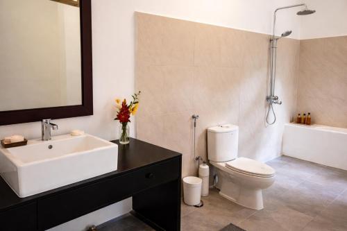 a bathroom with a sink and a toilet and a tub at Agwe Villa - Hikkaduwa in Dodanduwa