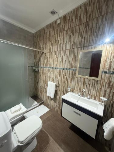 a bathroom with a white toilet and a sink at Apart Altos Del Pilar in Pilar