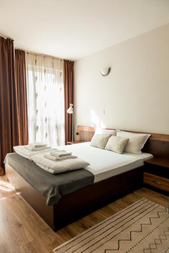 a bedroom with a large bed with white sheets and a window at Студио 3 Слънчево Утро in Hisarya
